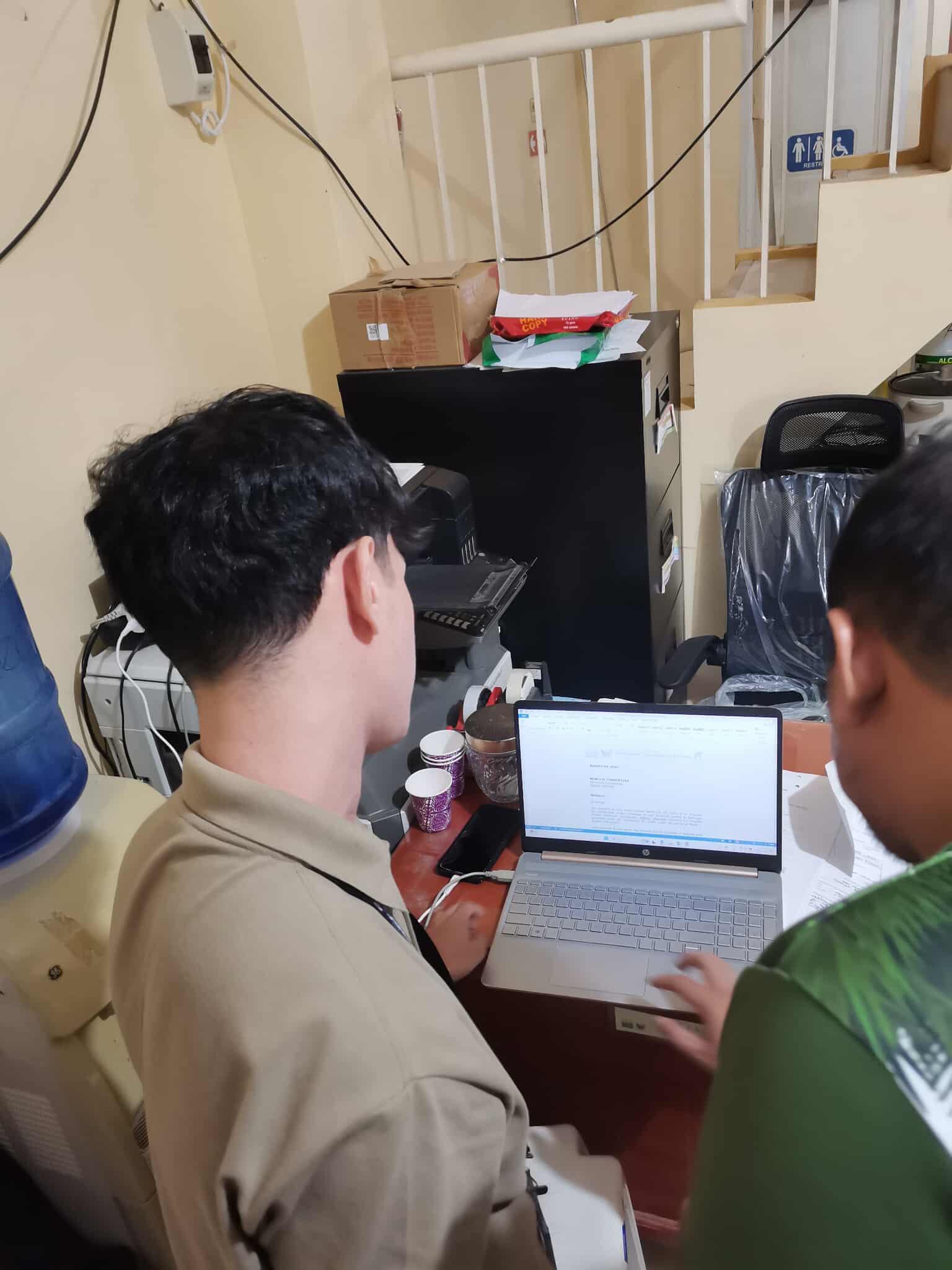 Zaldy working with office staff on a laptop during his DAR OJT